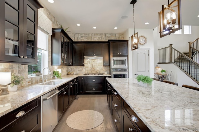 23451 E Rockinghorse Pkwy, Aurora, CO 80016 - kitchen with stainless steel appliances, a sink, light stone counters, light wood-style flooring, and recessed lighting