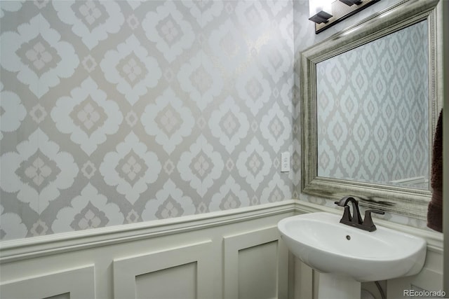 23451 E Rockinghorse Pkwy, Aurora, CO 80016 - bathroom with wallpapered walls, a sink, and a wainscoted wall