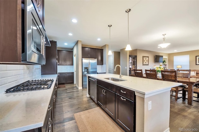 kitchen with a center island with sink, sink, stainless steel appliances, and hanging light fixtures