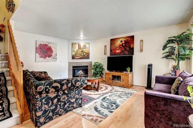 living room with a tiled fireplace and light hardwood / wood-style floors