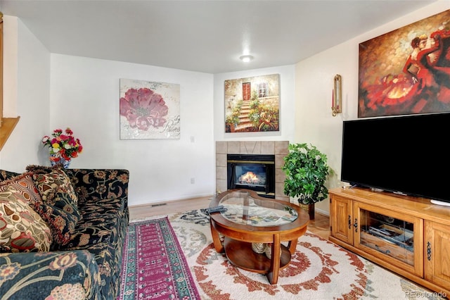 living room featuring a tile fireplace and light hardwood / wood-style flooring