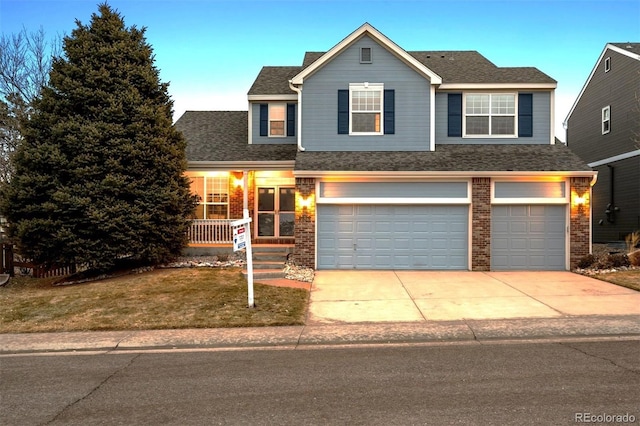 front facade with a garage, a front lawn, and covered porch