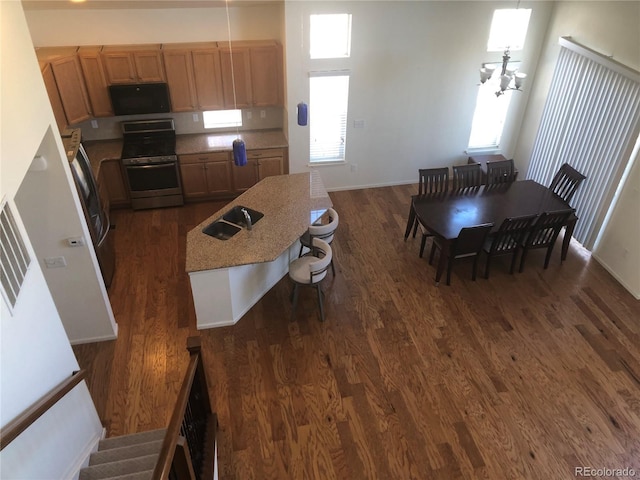 kitchen featuring stainless steel range, dark wood-style floors, a kitchen island, freestanding refrigerator, and a sink