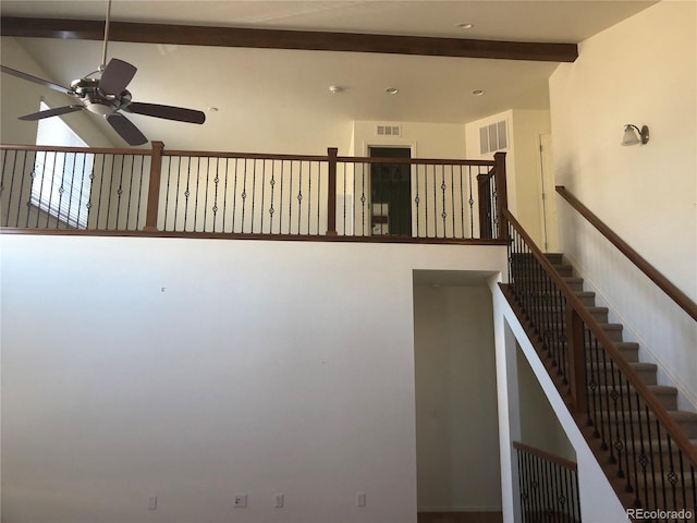 stairway with visible vents, vaulted ceiling with beams, and ceiling fan