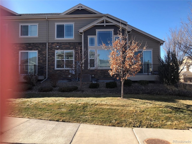 view of front of home with stone siding and a front lawn