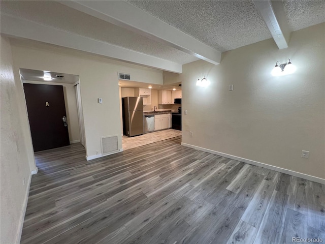 9995 E Harvard Ave Unit 261, Denver, CO 80231 - unfurnished living room with beamed ceiling, a textured ceiling, and wood finished floors