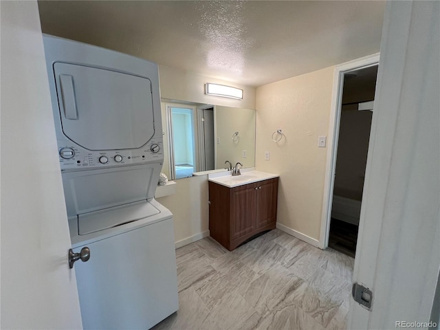 9995 E Harvard Ave Unit 261, Denver, CO 80231 - bathroom featuring stacked washer / drying machine, vanity, and a textured ceiling