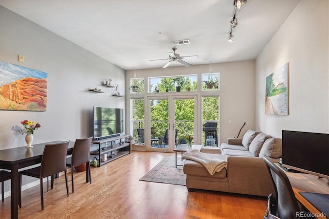 living room with light wood-type flooring, ceiling fan, track lighting, and french doors