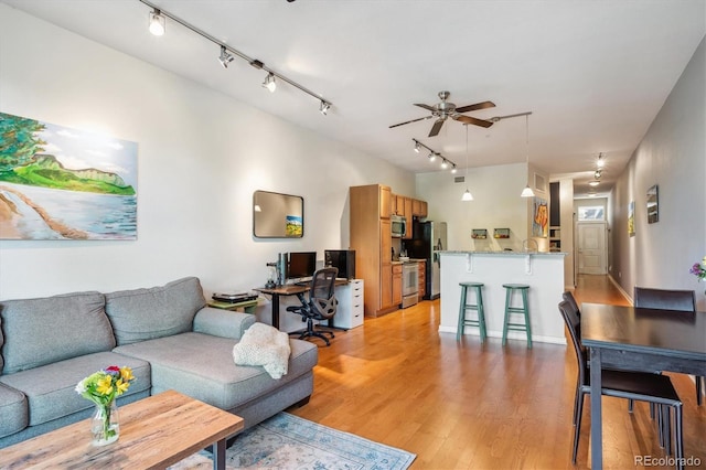 living room with ceiling fan and light hardwood / wood-style flooring