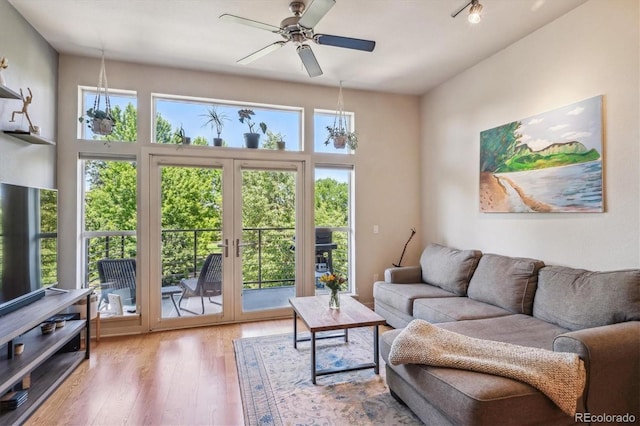 living room with french doors, a healthy amount of sunlight, ceiling fan with notable chandelier, and light hardwood / wood-style flooring