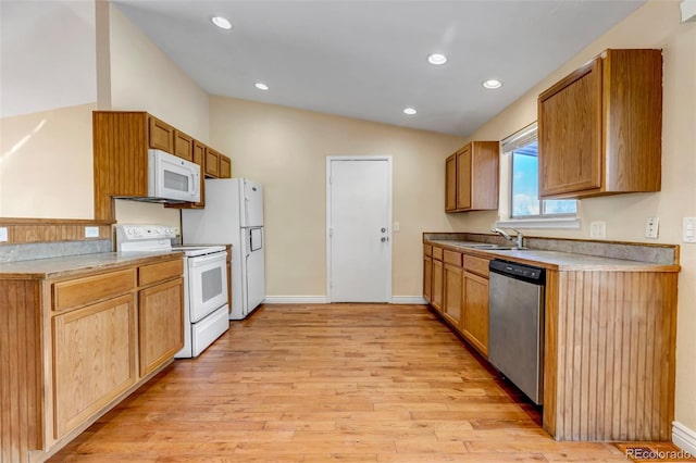 kitchen featuring vaulted ceiling, light wood-type flooring, sink, and white appliances