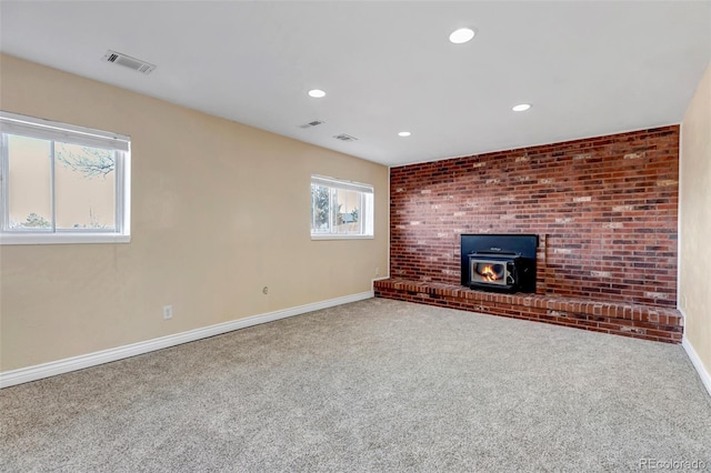 unfurnished living room featuring carpet and a wood stove