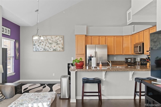 kitchen with stone countertops, a breakfast bar, hanging light fixtures, kitchen peninsula, and stainless steel appliances