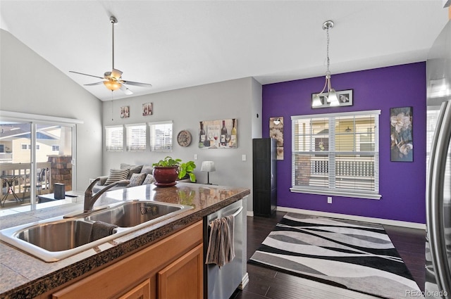 kitchen featuring appliances with stainless steel finishes, lofted ceiling, sink, hanging light fixtures, and dark wood-type flooring