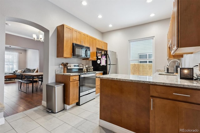 3429 N Adams St, Denver, CO 80205 - kitchen featuring appliances with stainless steel finishes, arched walkways, light stone countertops, recessed lighting, and light tile patterned floors