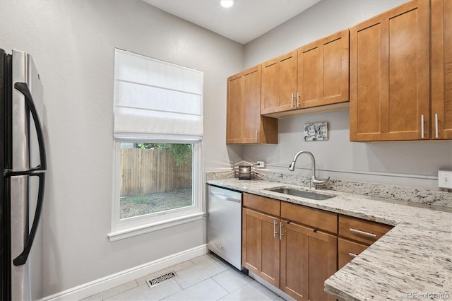 3429 N Adams St, Denver, CO 80205 - kitchen featuring appliances with stainless steel finishes, light stone counters, light tile patterned floors, and brown cabinetry