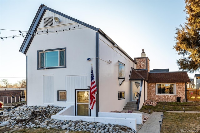 view of front of home with a chimney and stucco siding