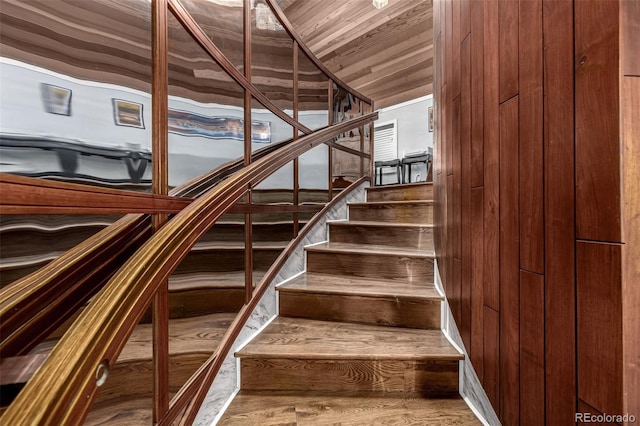 stairway with vaulted ceiling, wood walls, and wood ceiling