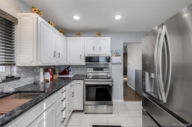 kitchen featuring light tile patterned floors, white cabinetry, stainless steel appliances, and decorative backsplash