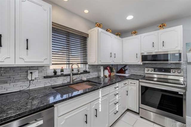 kitchen with stainless steel appliances, white cabinets, a sink, and backsplash