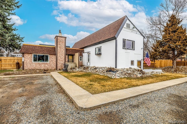 view of front of property featuring a shingled roof, fence, a chimney, and stucco siding