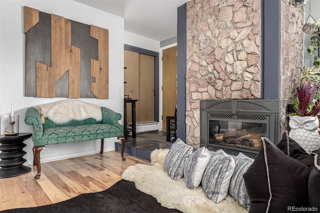 sitting room featuring a baseboard radiator, a fireplace, and wood finished floors