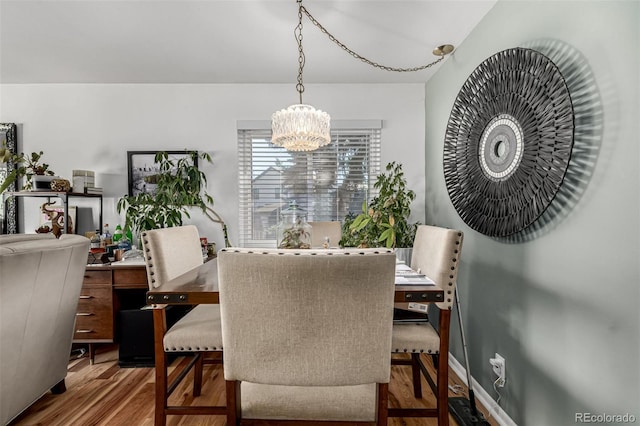 dining room with baseboards, an inviting chandelier, and wood finished floors