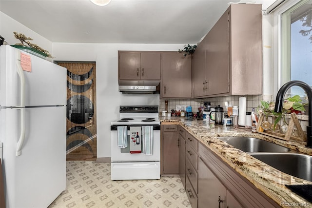 kitchen with light floors, backsplash, a sink, white appliances, and under cabinet range hood