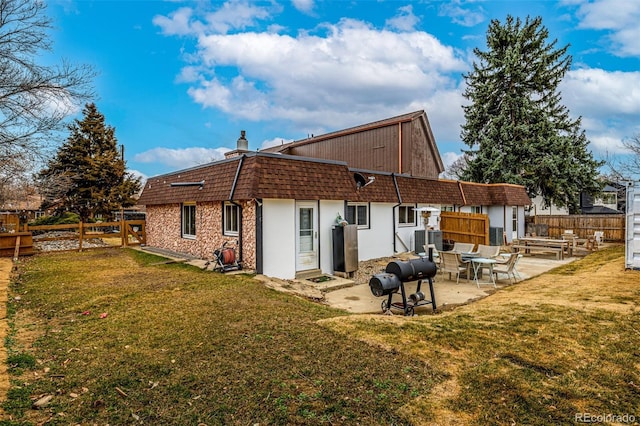 back of property featuring a patio area, a fenced backyard, mansard roof, and a lawn