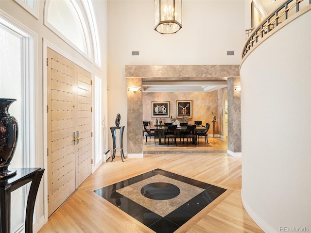 foyer featuring a high ceiling, wood finished floors, visible vents, and an inviting chandelier