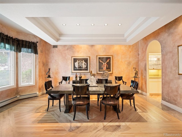 dining space featuring light parquet flooring, baseboard heating, and a raised ceiling