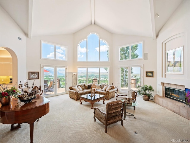 living room featuring french doors, a tile fireplace, and high vaulted ceiling