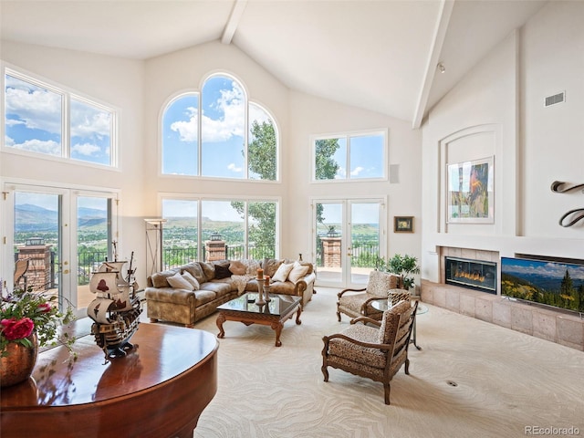 carpeted living room with high vaulted ceiling, a wealth of natural light, and a tile fireplace