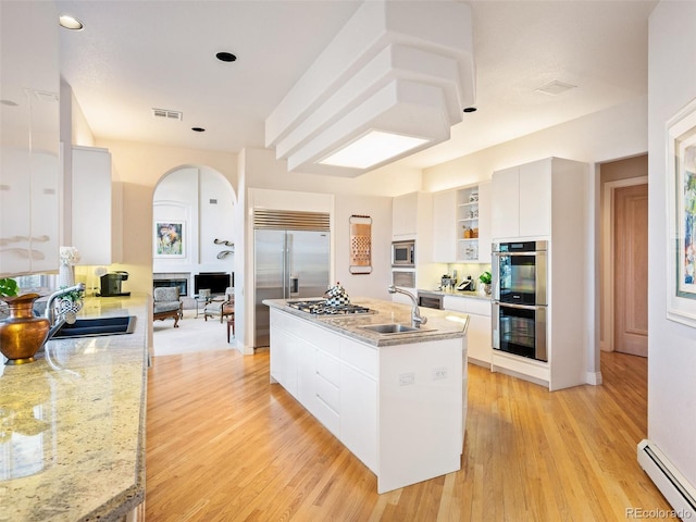 kitchen with white cabinetry, a baseboard radiator, sink, and built in appliances