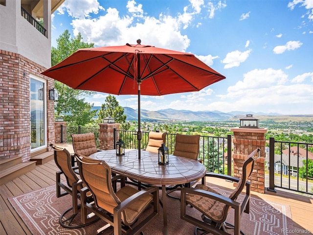 wooden terrace with outdoor dining space and a mountain view