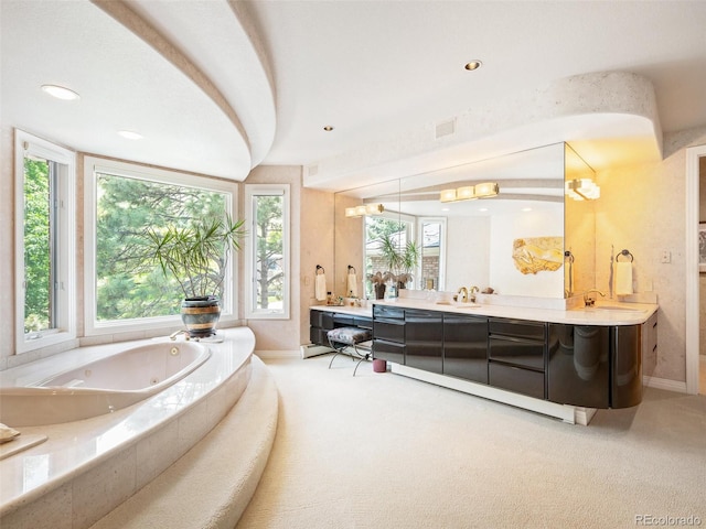 bathroom with tiled bath, vanity, and a wealth of natural light