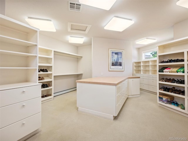 walk in closet with a baseboard heating unit and light carpet