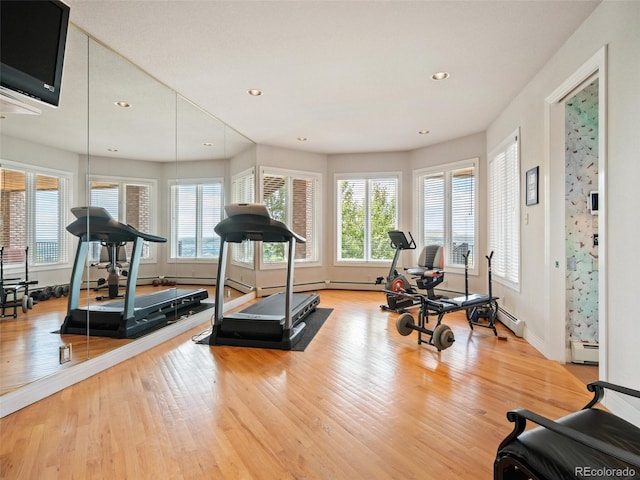 exercise area featuring a baseboard heating unit and light hardwood / wood-style flooring