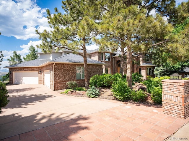 view of front of home with a garage, driveway, brick siding, and a shingled roof