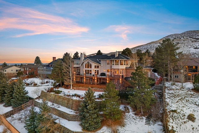 snow covered house featuring a deck with mountain view