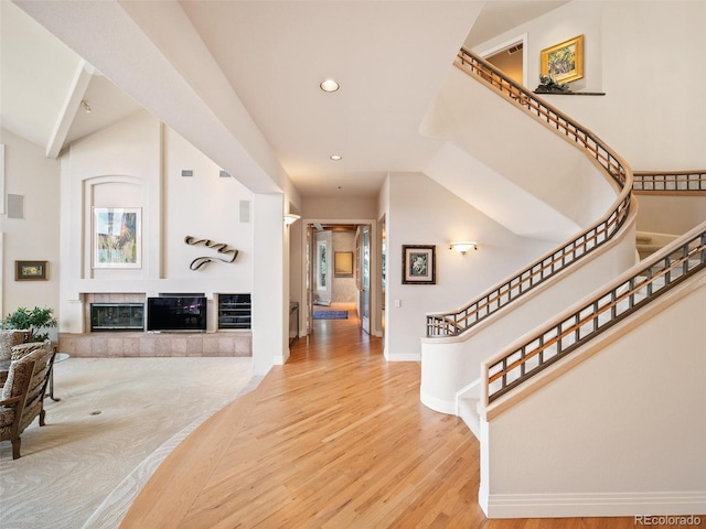 foyer featuring recessed lighting, wood finished floors, baseboards, stairs, and a tiled fireplace