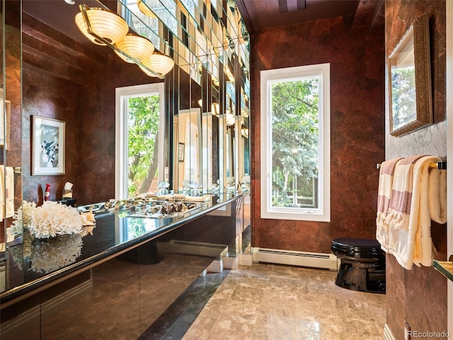 bathroom with toilet, marble finish floor, baseboards, and a baseboard heating unit