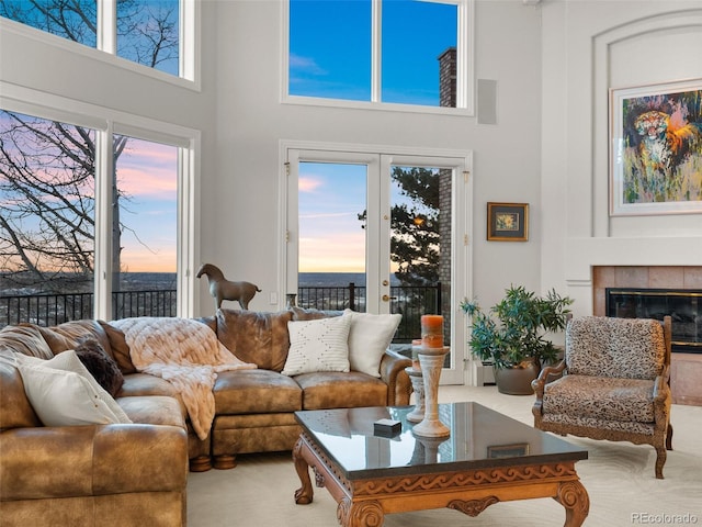 living room featuring a towering ceiling, a fireplace, and french doors