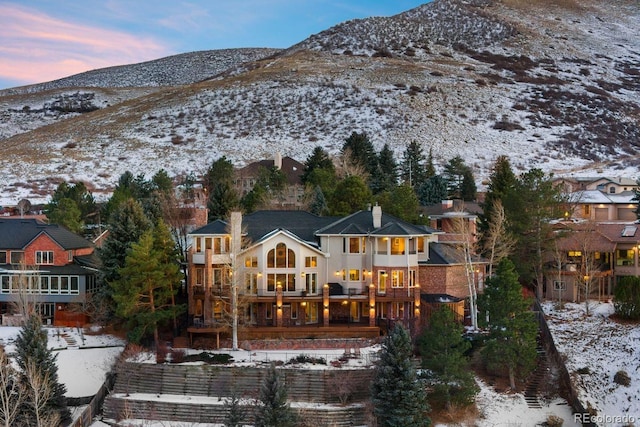 snow covered rear of property featuring a chimney and a mountain view