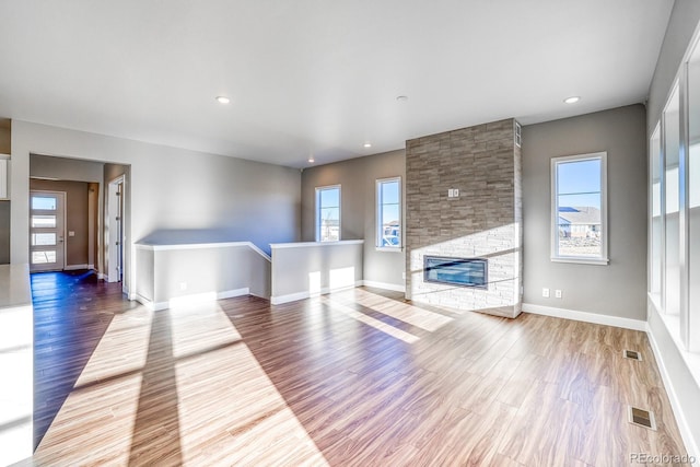 unfurnished living room with a wealth of natural light, a fireplace, and wood-type flooring