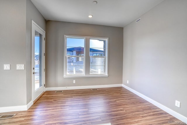 spare room with light wood-type flooring and plenty of natural light