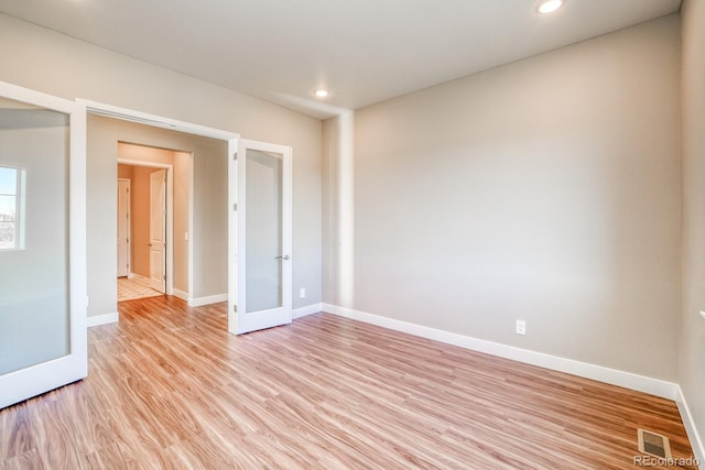 empty room with french doors and light hardwood / wood-style flooring