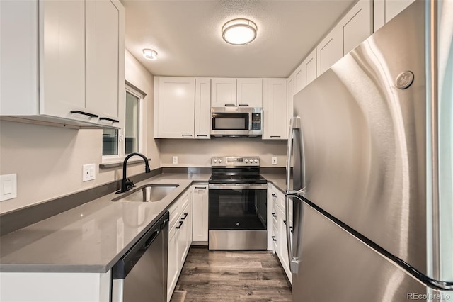 kitchen featuring white cabinets, appliances with stainless steel finishes, dark hardwood / wood-style flooring, and sink