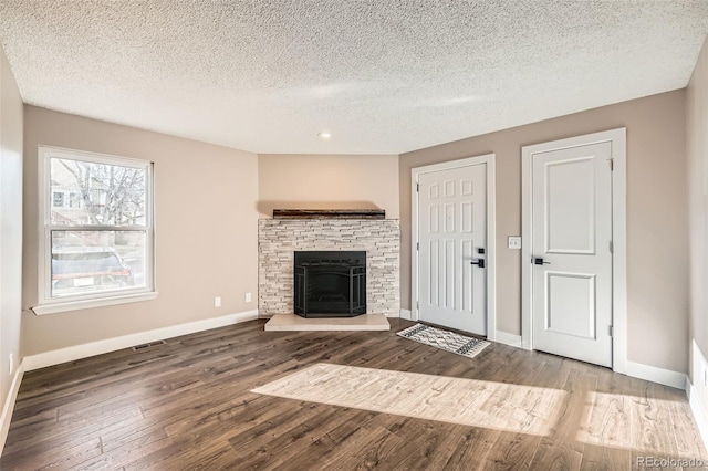 unfurnished living room featuring hardwood / wood-style floors, a textured ceiling, and a stone fireplace