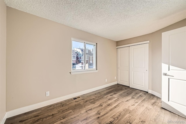 unfurnished bedroom featuring a textured ceiling, light hardwood / wood-style flooring, and a closet